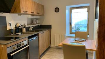 Une cuisine compacte avec des meubles en bois, un four encastré et une fenêtre donnant sur l’extérieur.