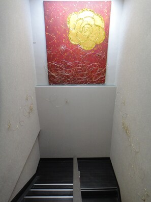 A narrow stairway with a red and gold abstract painting on the wall above. - Fantastic Hostel (Taichung)