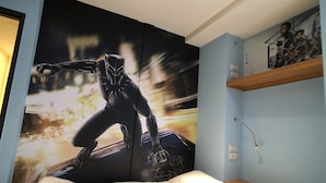 A bedroom with a large poster of a character on the wall, a bed with white bedding, and a shelf with a picture. - Fantastic Hostel (Taichung)