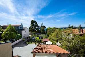 A residential area with a clear blue sky, a tiled roof, and lush greenery.