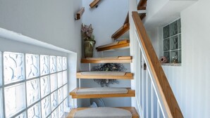 A staircase with wooden steps and beige carpet runners, leading to a landing with a window with patterned glass.