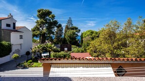 A residential area with a white house, a red-tiled roof, and lush greenery.