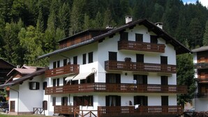 A multi-story building with balconies, a flat roof, and a white exterior. - Casa Campanula (Falcade)