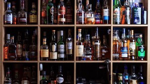 A wooden liquor cabinet with multiple shelves containing various bottles of alcohol.