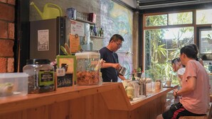 A café with a wooden counter, various food items, and a mural on the wall. - Yuan Qi Hostel (Tainan)