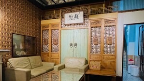 A traditional room with a sofa, a glass-top table, and a wooden cabinet with intricate designs. - Yuan Qi Hostel (Tainan)