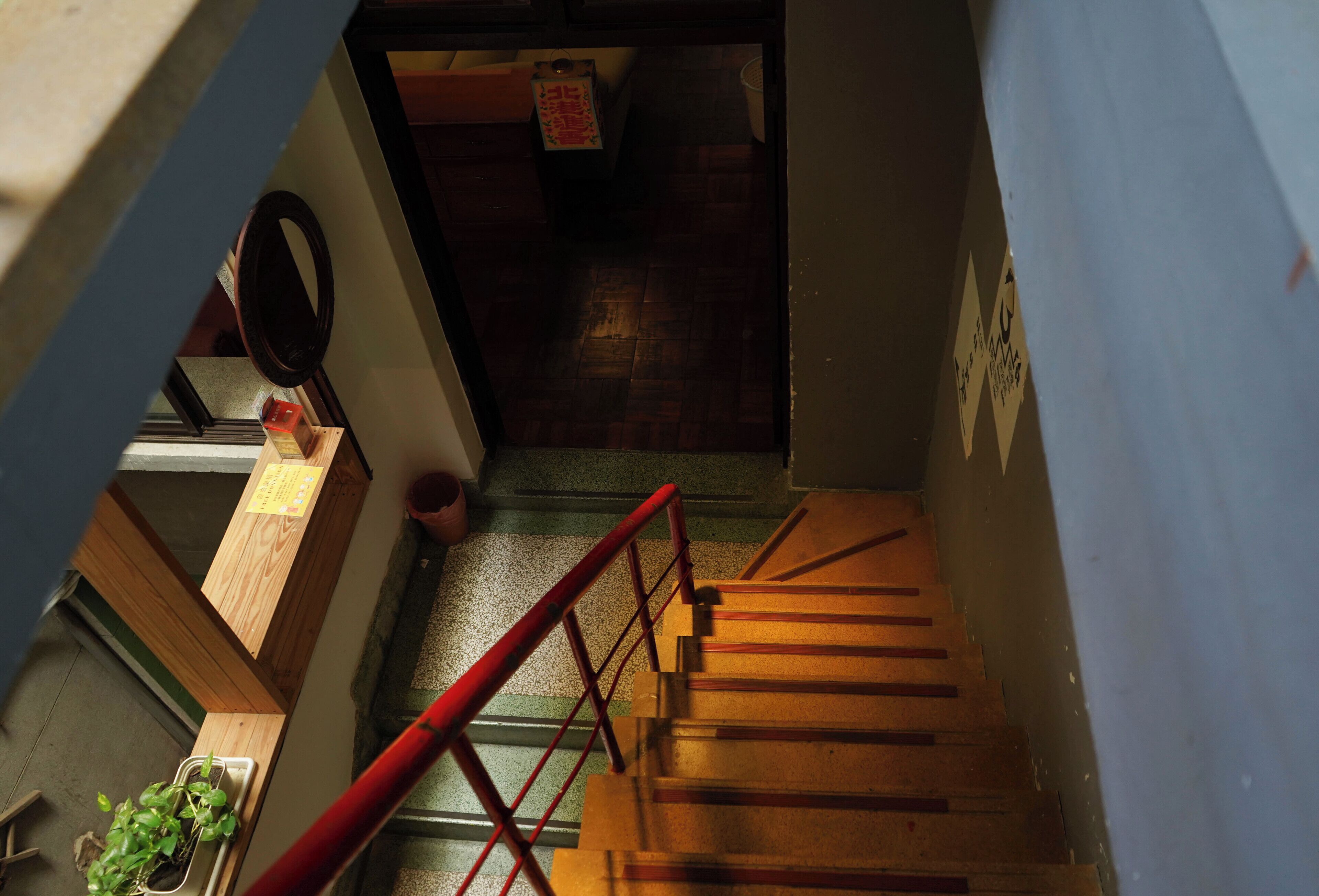 A wooden staircase with a red handrail leading to a landing.