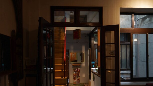 A narrow hallway with wooden doors and a small dog bed. - Yuan Qi Hostel (Tainan)
