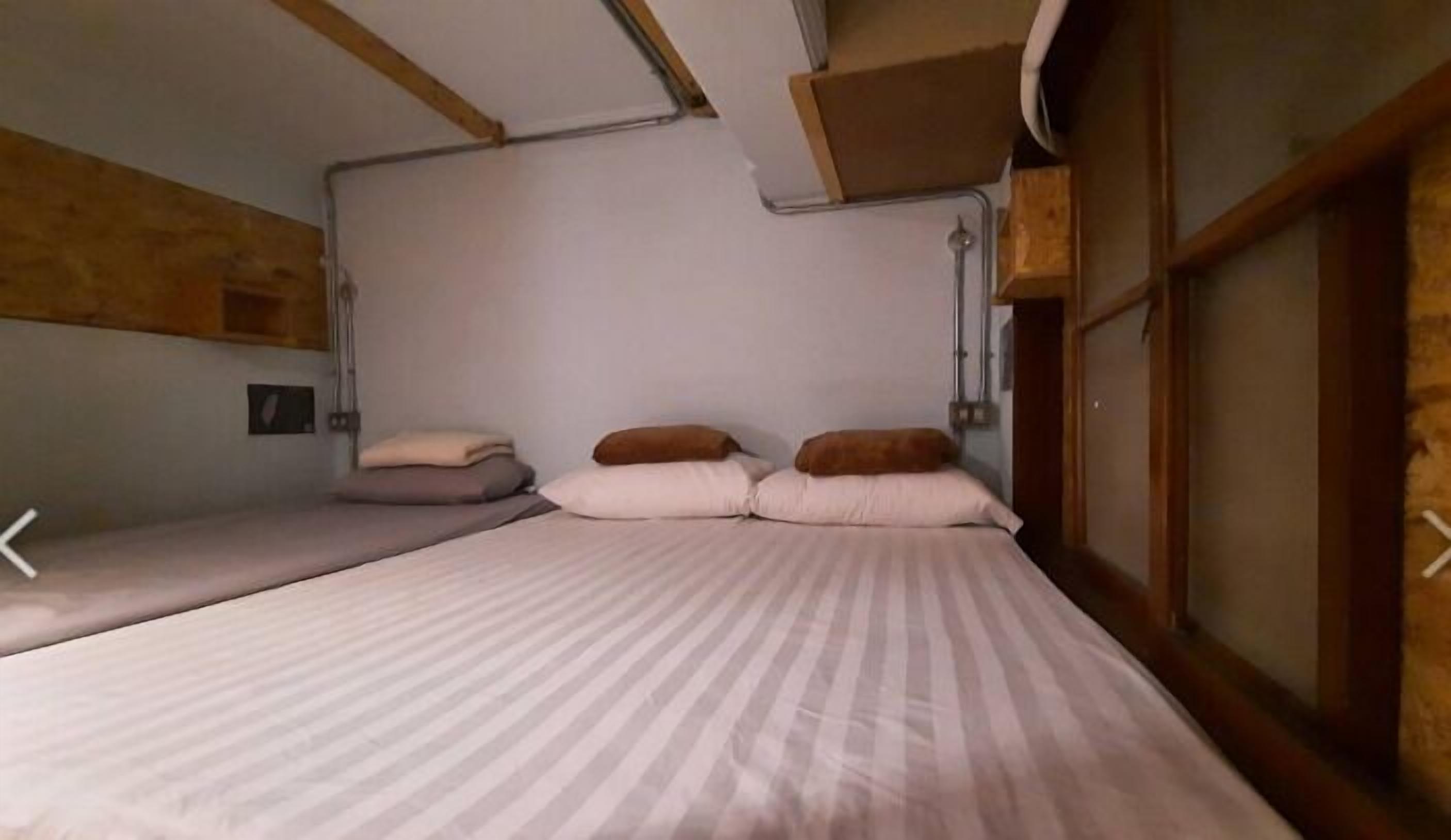 Una habitación con dos camas, paredes de madera y un ventanal.