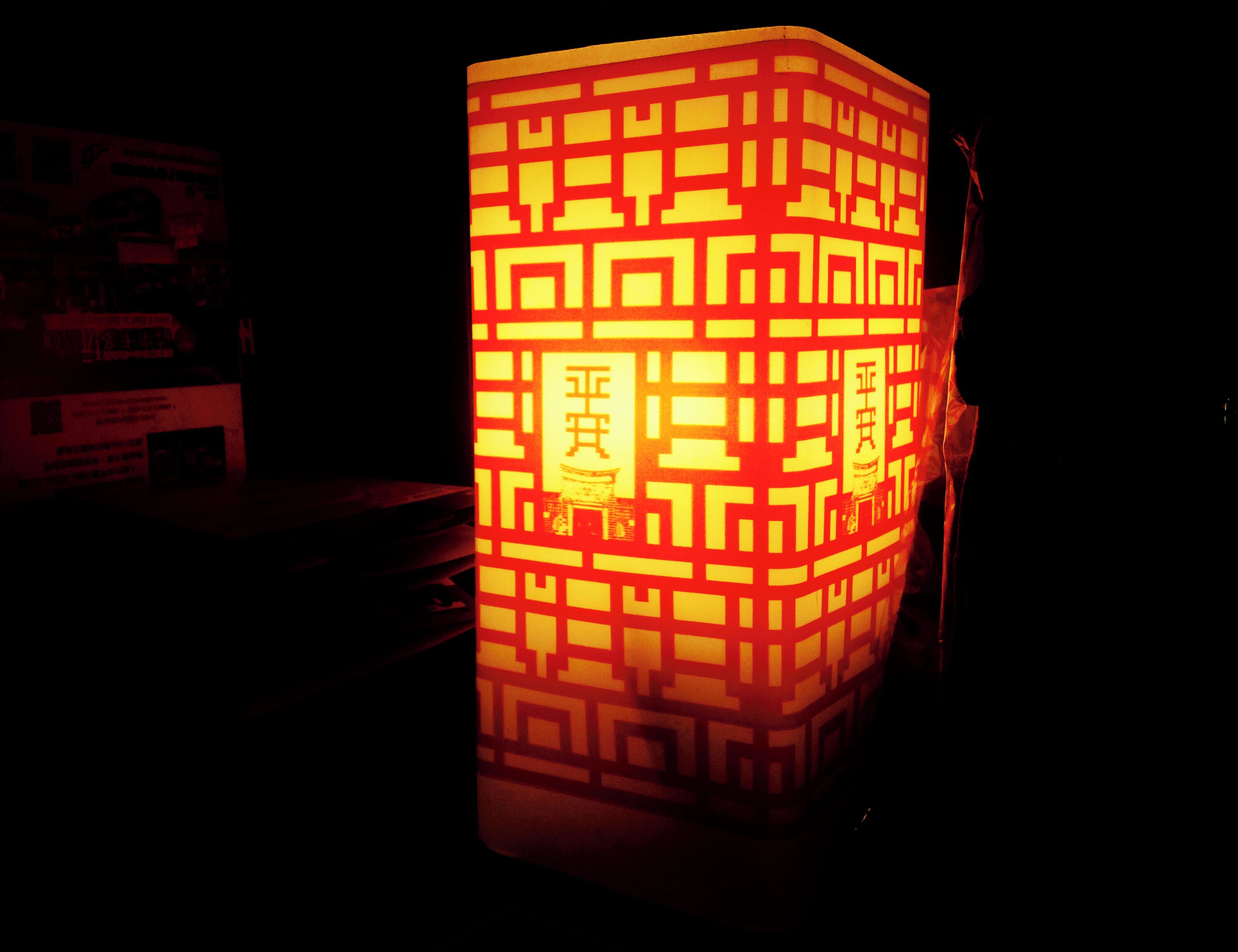 A traditional lantern with intricate patterns and Chinese characters, illuminated in a dark setting.