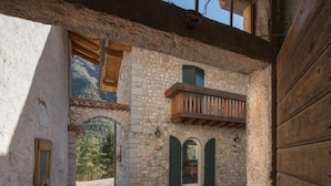 An interior courtyard with stone flooring, wooden beams, and a balcony with a wooden railing.