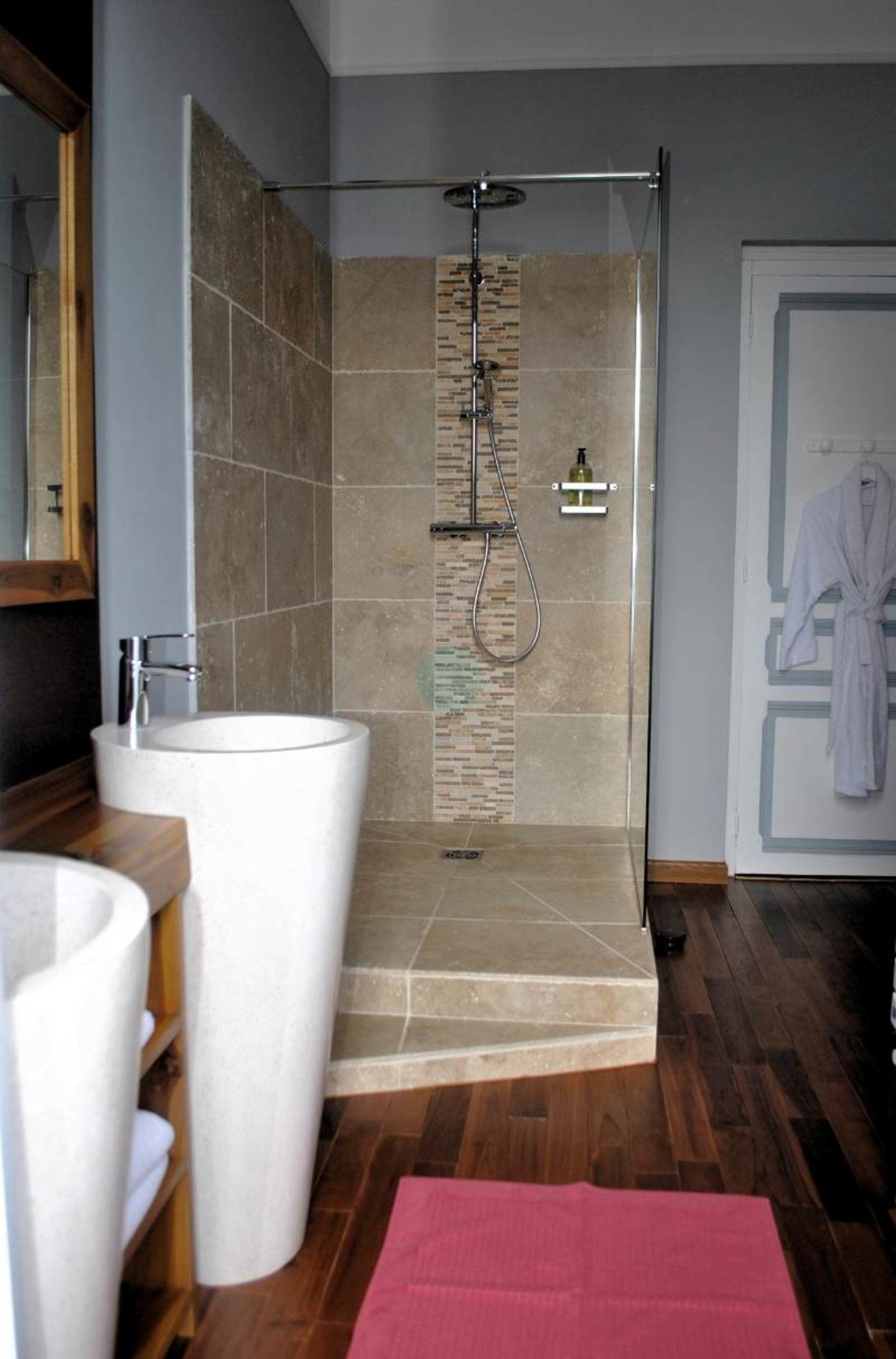 Un baño moderno con una ducha amplia, un lavamanos blanco y un mueble de tocador de madera.