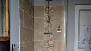 Un baño moderno con una ducha amplia, un lavamanos blanco y un mueble de tocador de madera.