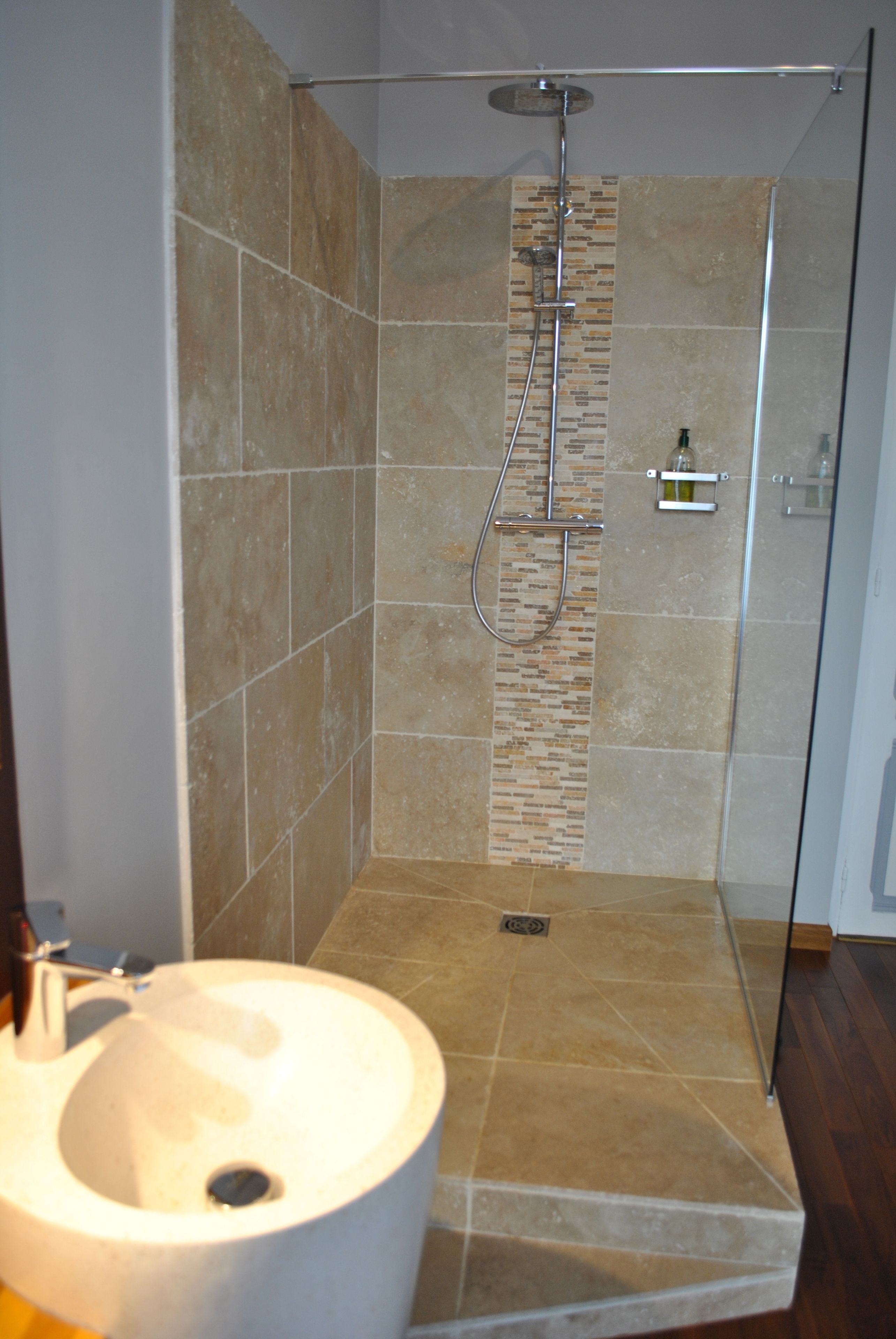 Un baño con ducha, lavamanos y puerta de vidrio.