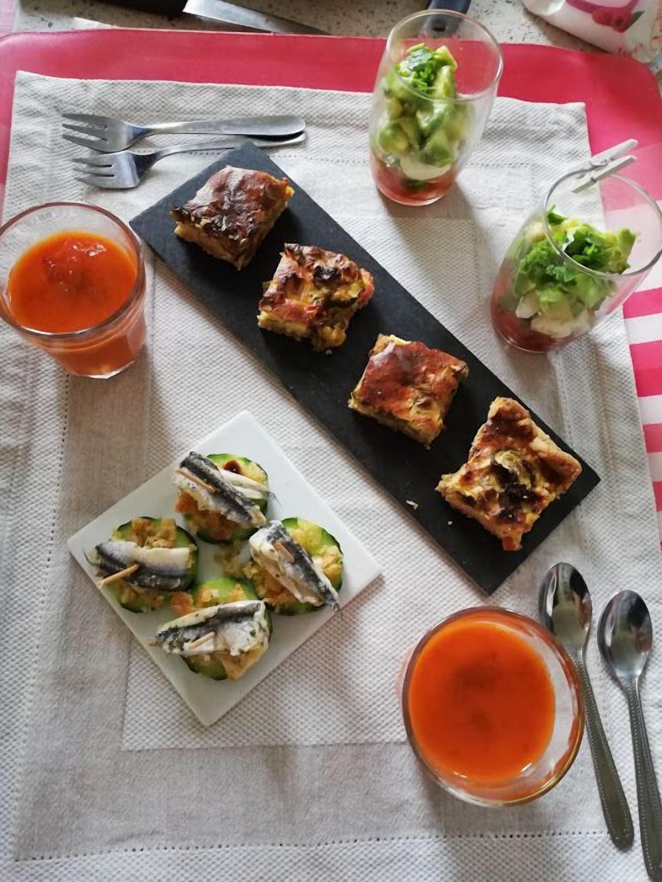 Un plato con pescado, ensalada y salsa de tomate sobre una mesa con servilleta y cubiertos.