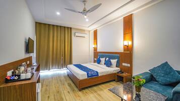 Une chambre d’hôtel comprenant un lit, une table de chevet, une commode et un coin salon avec un canapé et une table basse.