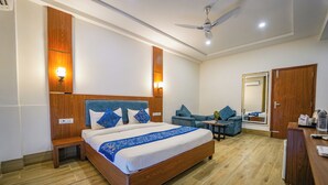 Una habitación de hotel con una cama grande, una mesita, una silla, un escritorio y un armario.