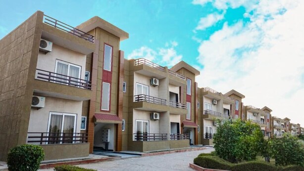 Una hilera de edificios de apartamentos modernos con balcones, unidades de aire acondicionado y un acceso pavimentado.