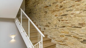 Una escalera con barandillas blancas que lleva a un muro de piedra.
