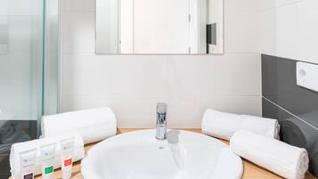 Uma casa de banho moderna com uma pia branca, um espelho em cima e duas toalhas no balcão.