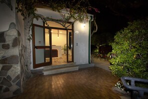 A building entrance with a stone facade, a wooden door, and a small porch area.