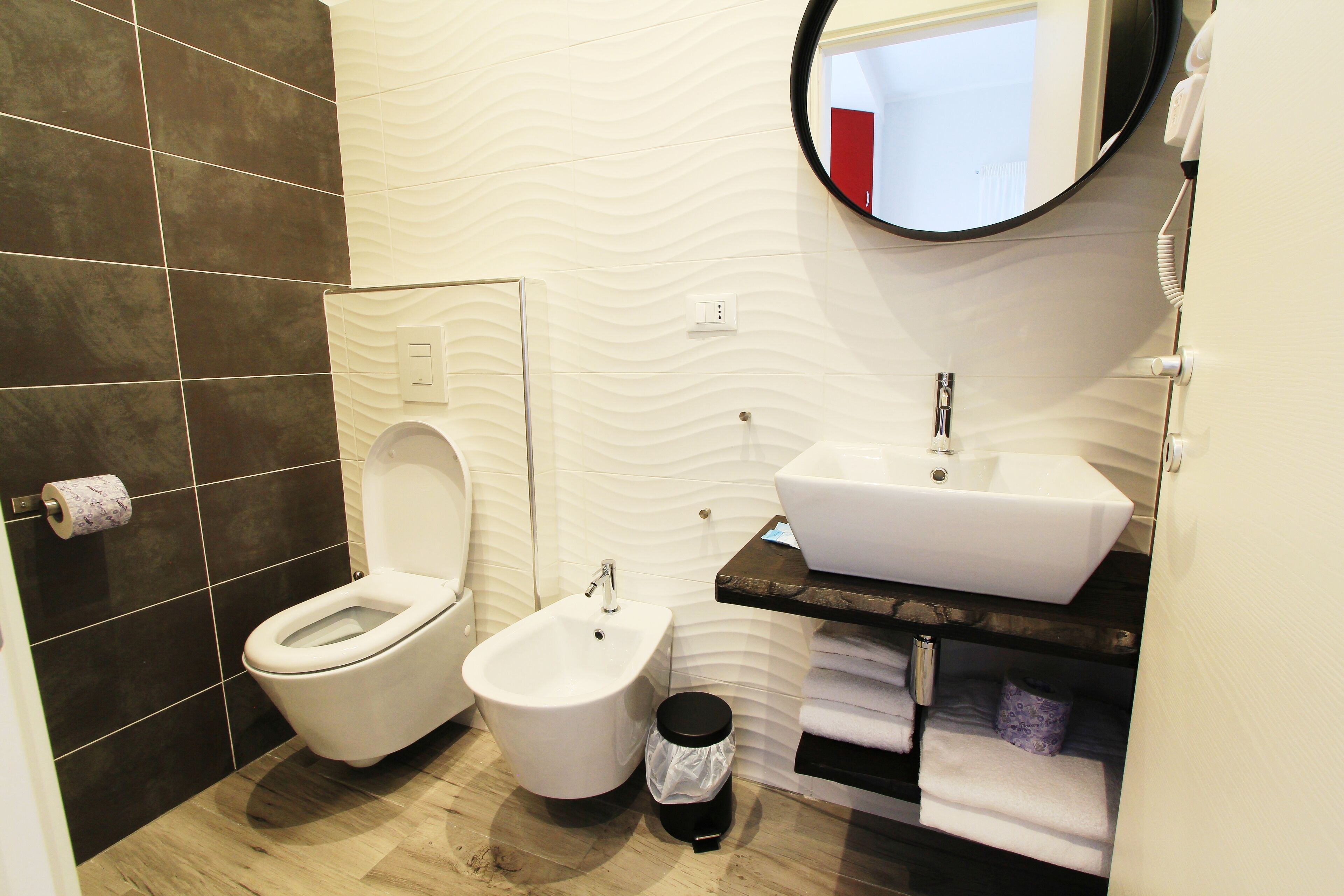A modern bathroom with a bidet, a sink, and a mirror.