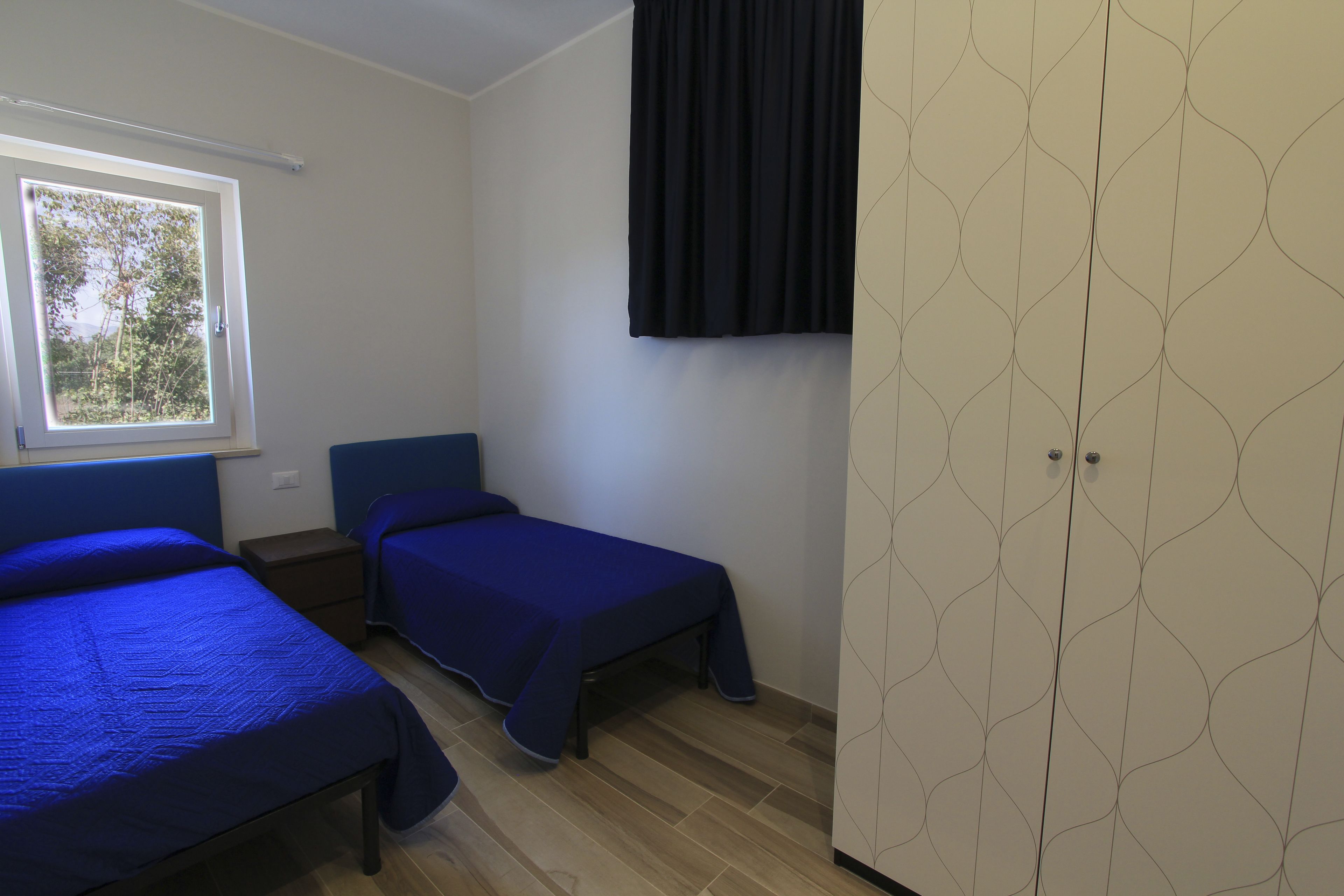 A room with two beds, a wardrobe, and a window.