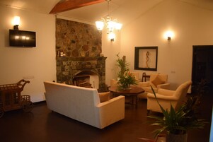 Una sala acogedora con chimenea de piedra, televisor montado en la pared y una araña.
