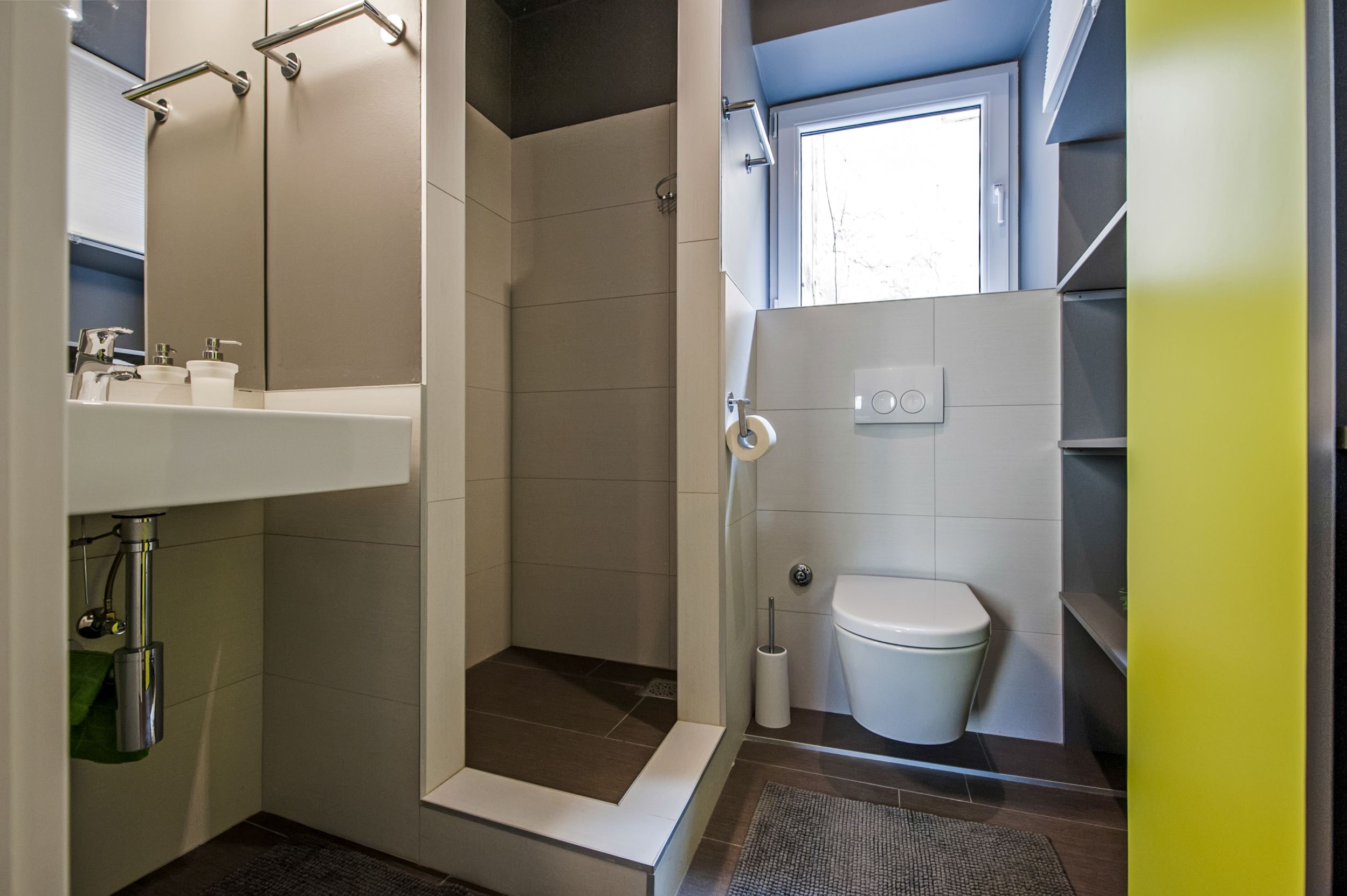 A modern bathroom with a shower, toilet, and sink.