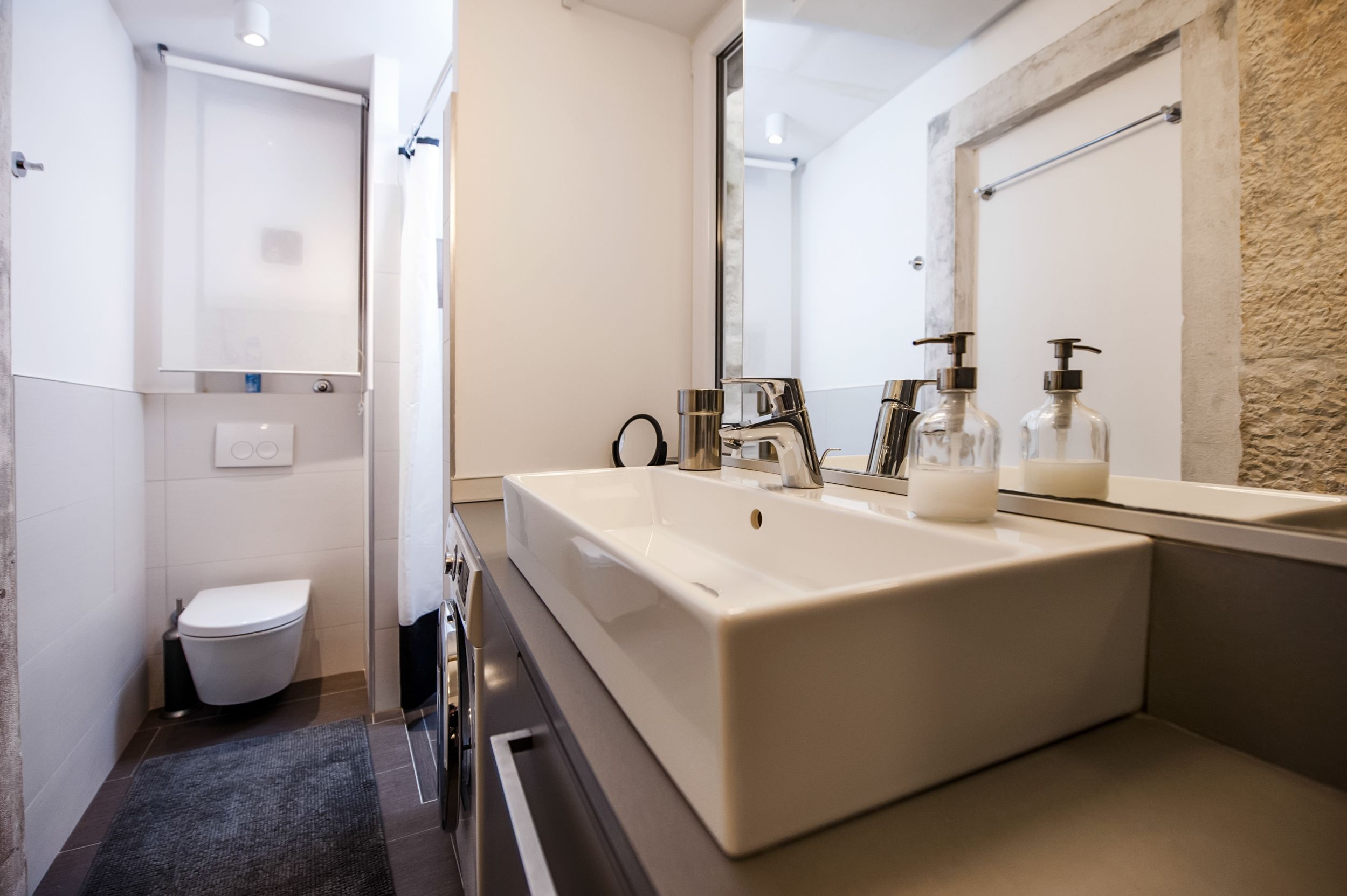 Un baño moderno con un lavamanos rectangular grande, un inodoro y un espejo.