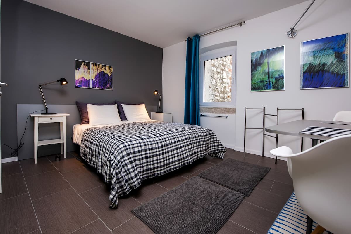 A modern bedroom with a bed, bedside tables, a desk, and chairs.
