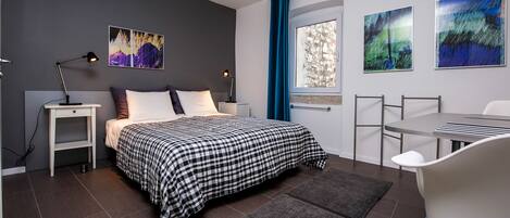 A modern bedroom with a bed, bedside tables, a desk, and chairs.
