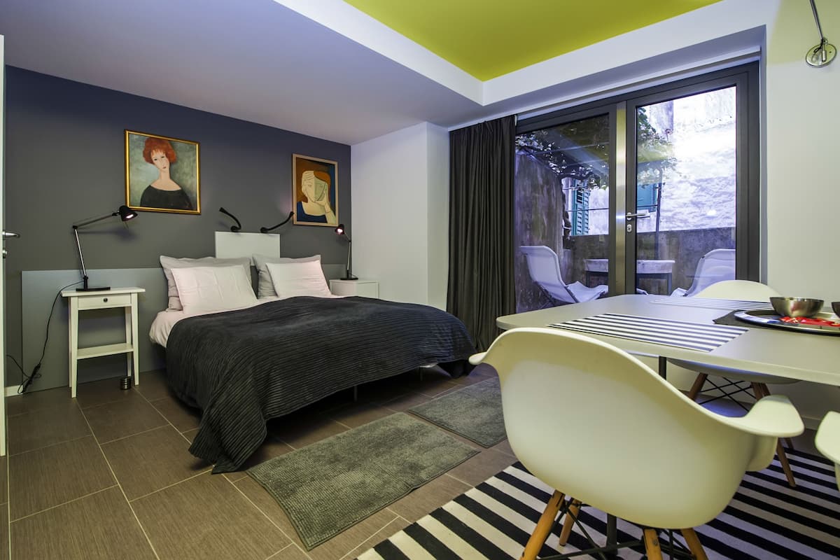 A modern bedroom with a bed, bedside tables, a desk, and chairs.