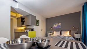 Een kleine hotelkamer met een bed, nachtkastjes, een bureau en een kitchenette.