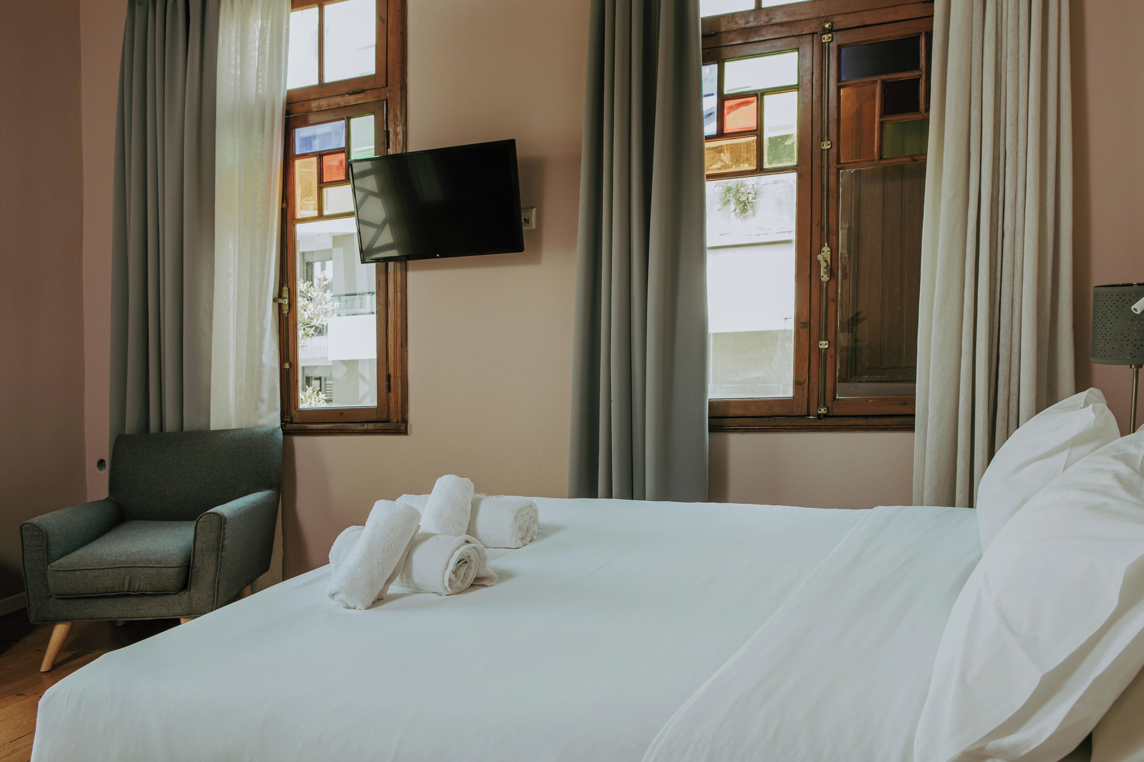 Una habitación de hotel con cama, una silla, un televisor y cortinas.