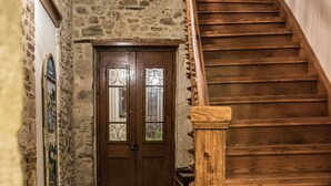 A hallway with a patterned floor, a wooden staircase, and a stone wall.