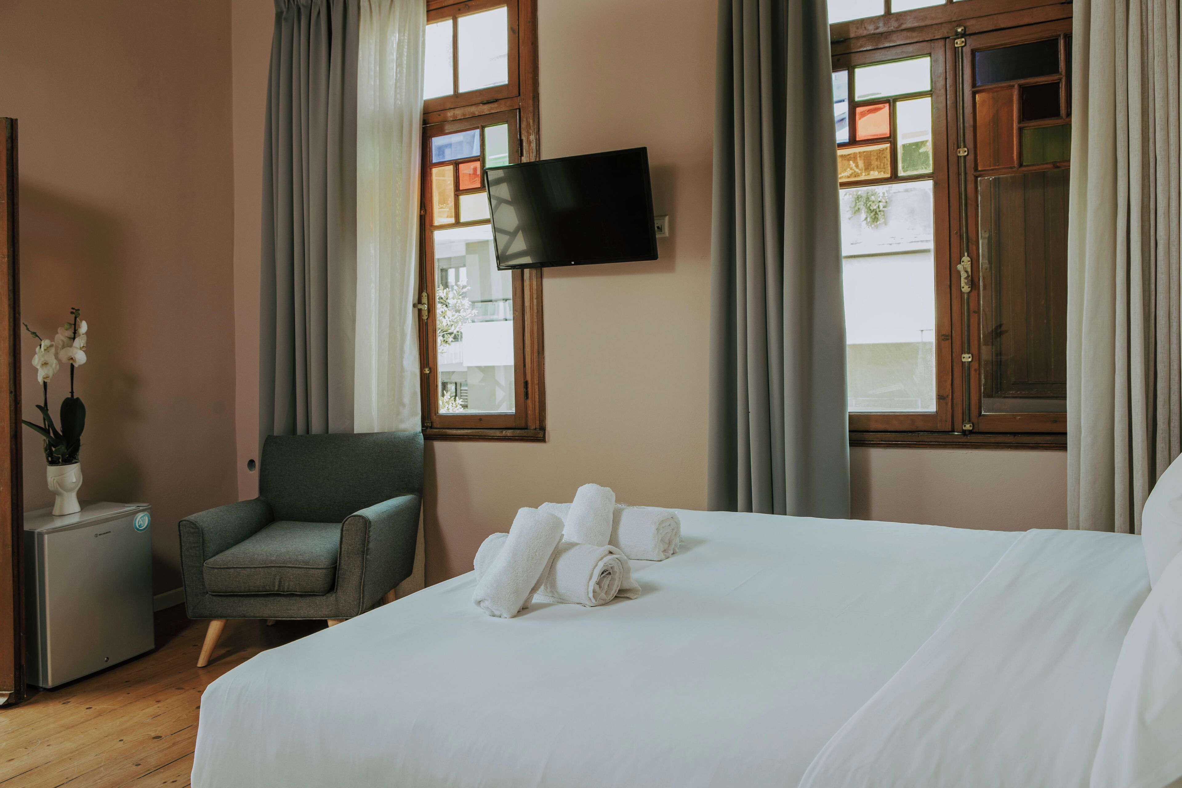 A hotel room with a bed, a chair, a TV, and a small table with a plant.