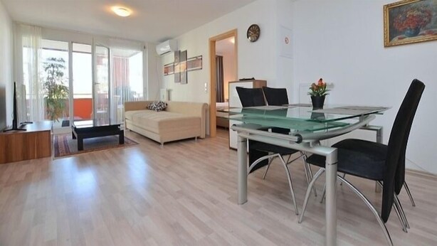 A modern living room with a glass dining table, black chairs, a beige sofa, and a large window. - Apartment 2 Zimmer Flughafen Stuttgart (Filderstadt)