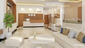A modern hotel lobby with a reception desk, seating area, and a large window with flowers. - Tram Anh Hotel (Quy Nhon)