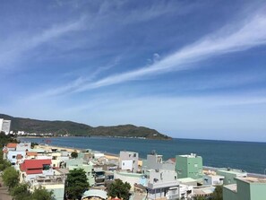 A coastal town with buildings close to the sea, a clear sky, and hills in the background. - Tram Anh Hotel (Quy Nhon)