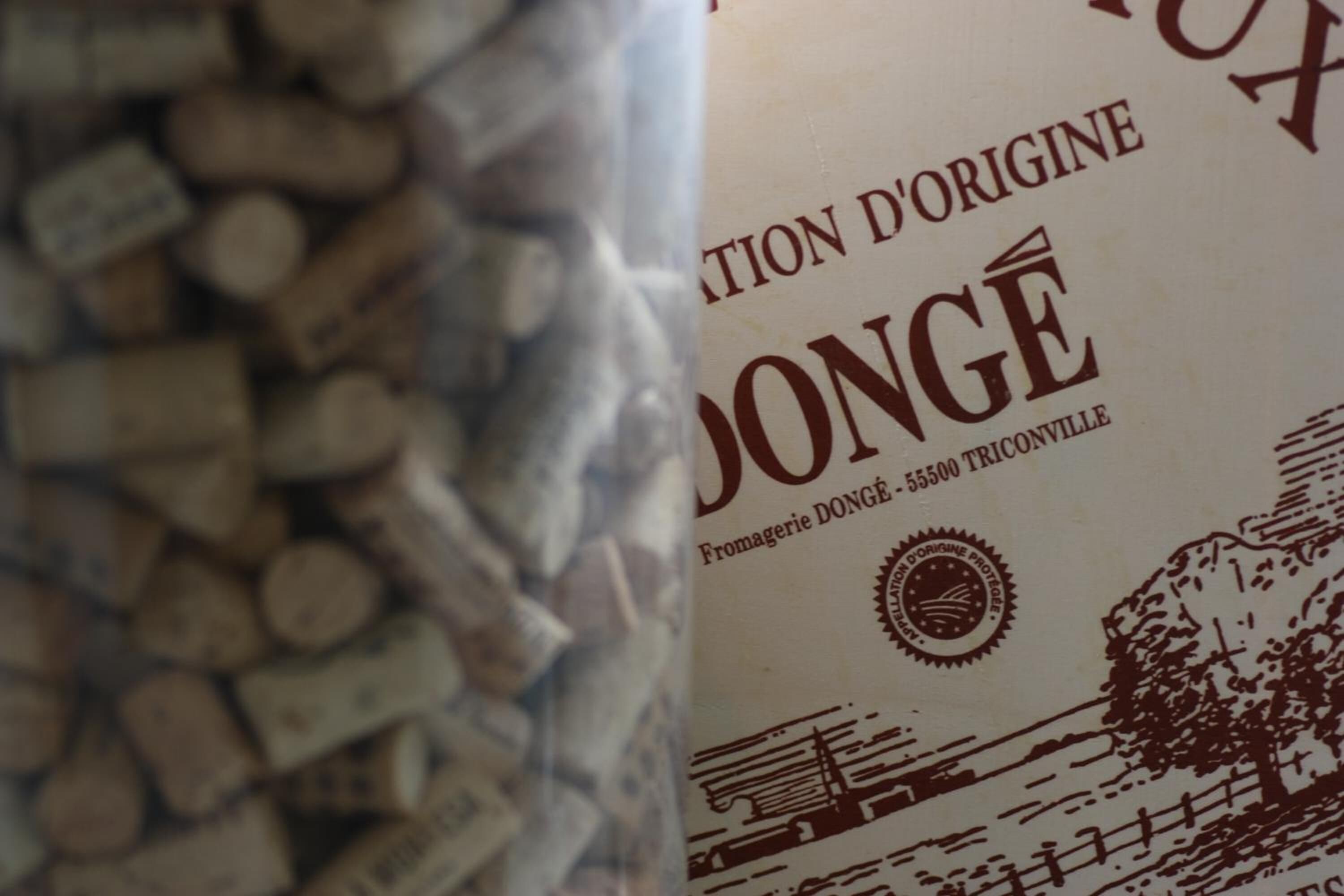 Un libro con el título 'Fromagerie Dongé' y un logotipo que muestra un árbol y un edificio.