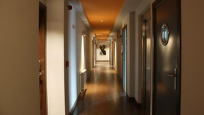 Passadís d'hotel amb terra de fusta, portes a ambdós costats i un senyal que indica la sortida.