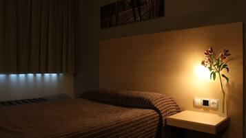 A hotel room with a bed, a bedside table with a lamp, and a painting on the wall.