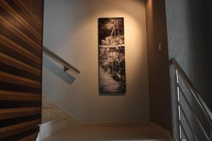 Uma escadaria com corrimão de madeira e um quadro na parede retratando uma ponte.