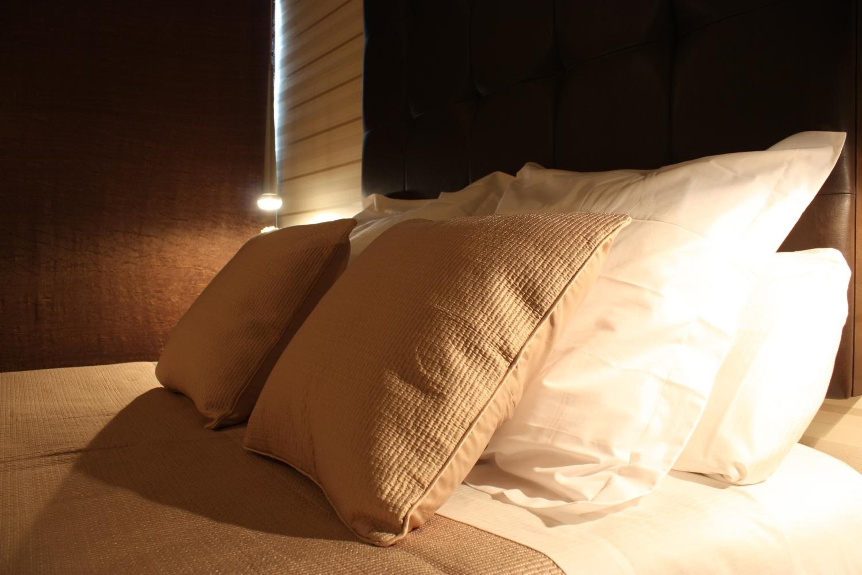 Een netjes opgemaakt bed met twee kussens en een dekbed.