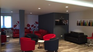 Un área de estar moderna con sofás rojos y negros, una mesa redonda y una obra de arte colgada en la pared.