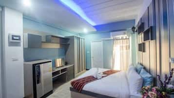 A modern hotel room with a bed, a built-in desk, and a wardrobe.