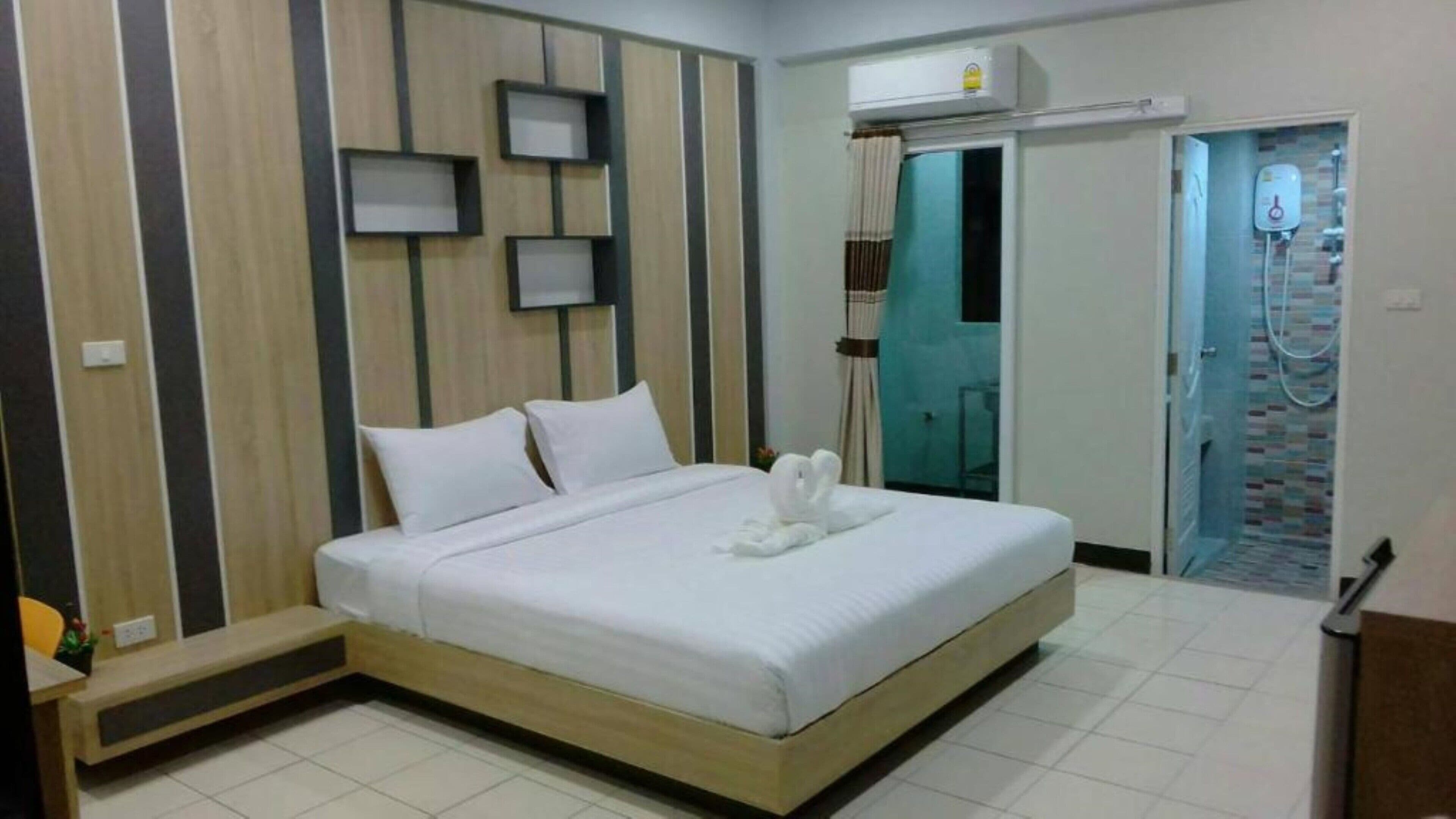 A hotel room with a bed, a shower area, and a reception desk.