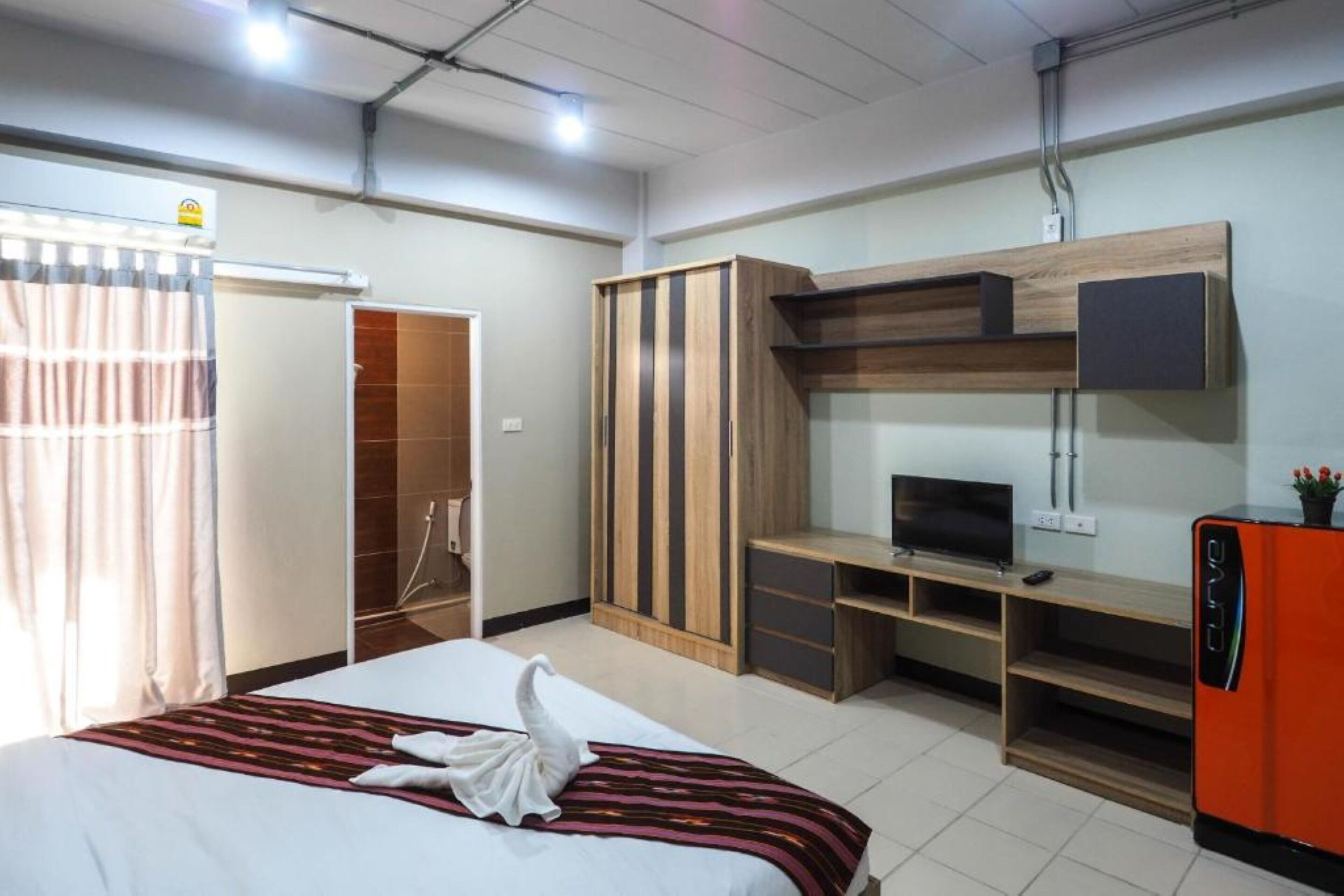 A hotel room with a bed, a TV, a wardrobe, and a desk.