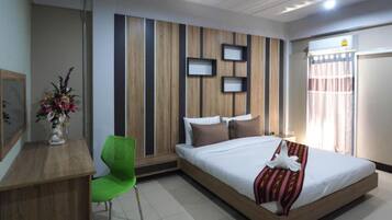 Ein modernes Hotelzimmer mit einem hölzernen Bett, einem Schreibtisch, einem grünen Stuhl und einer dekorativen Wandverkleidung.